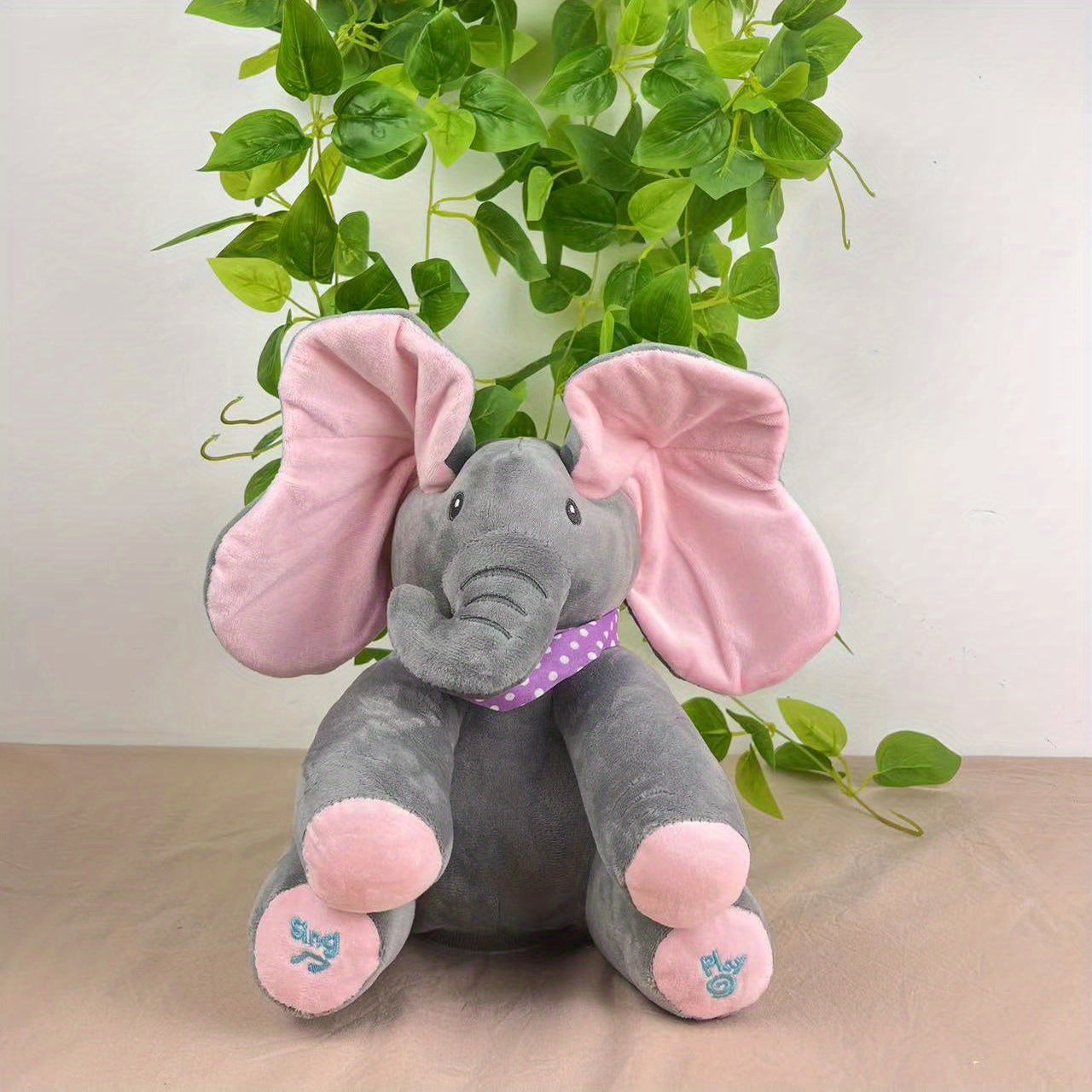 Plush elephant toy with pink ears and feet on a neutral background