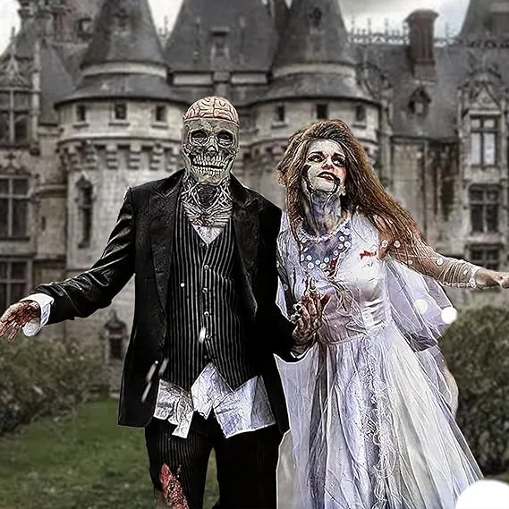 Two people in zombie wedding costumes standing in front of a castle.