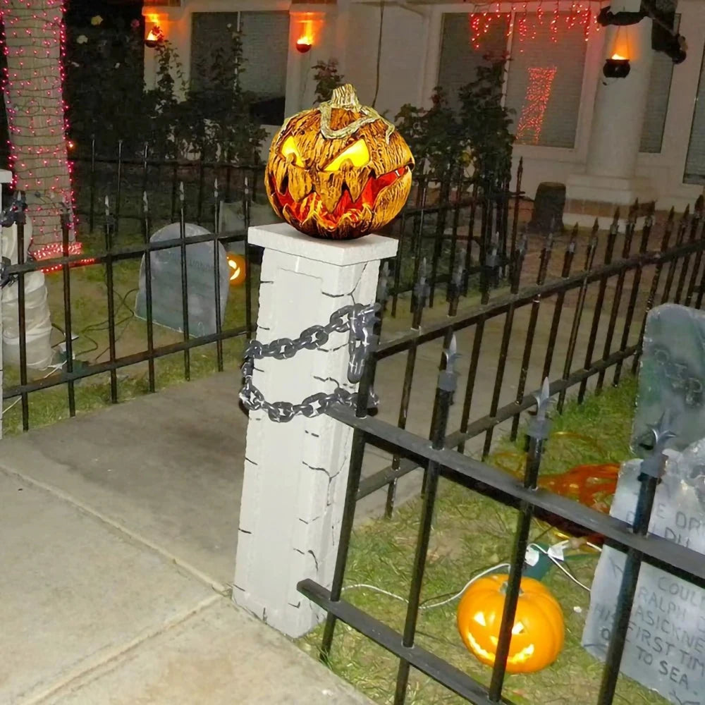 decorations including a pumpkin on a stone pedestal with a black chain, tombstones, and pumpkins in front of a house.